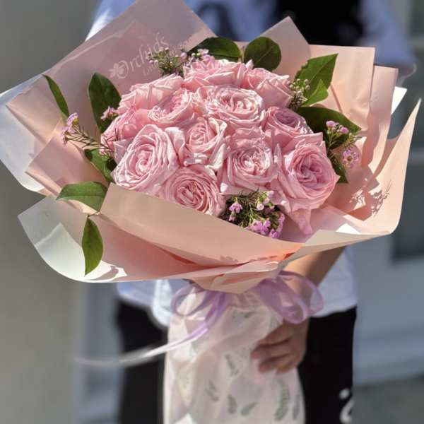Pink rose bouquet wrapped in pastel paper with a lavender ribbon