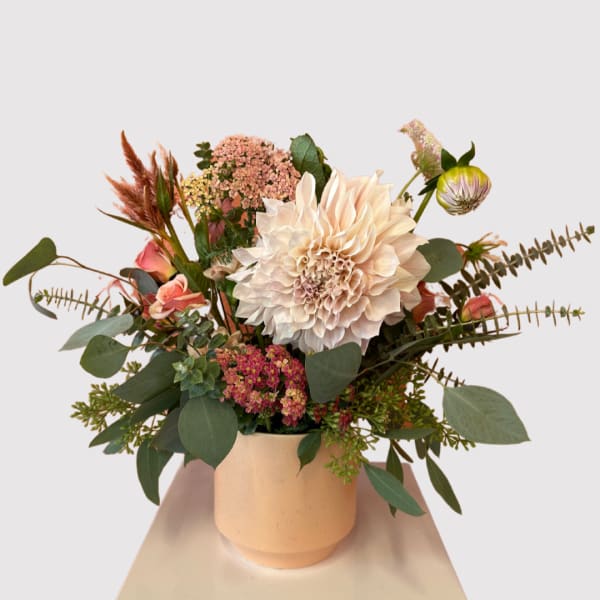 Mixed bouquet with a large cream dahlia in a peach vase