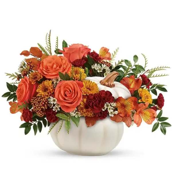 Orange and red floral arrangement in a white pumpkin vase