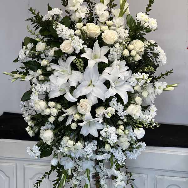 Large white floral standing spray with lilies and roses on an easel