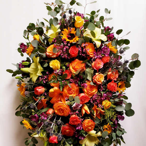 Large bouquet of orange and yellow roses with lilies and greenery