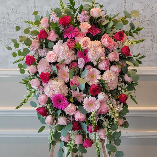 Large pink and red floral arrangement on an easel