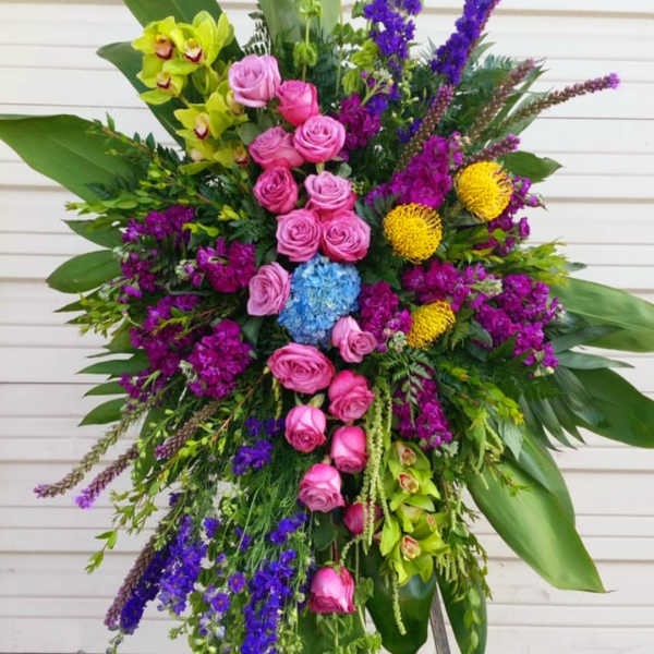Large standing floral spray with pink roses, purple blooms, and green orchids