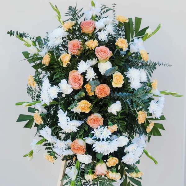 Standing floral spray with peach roses, white daisies, and yellow carnations