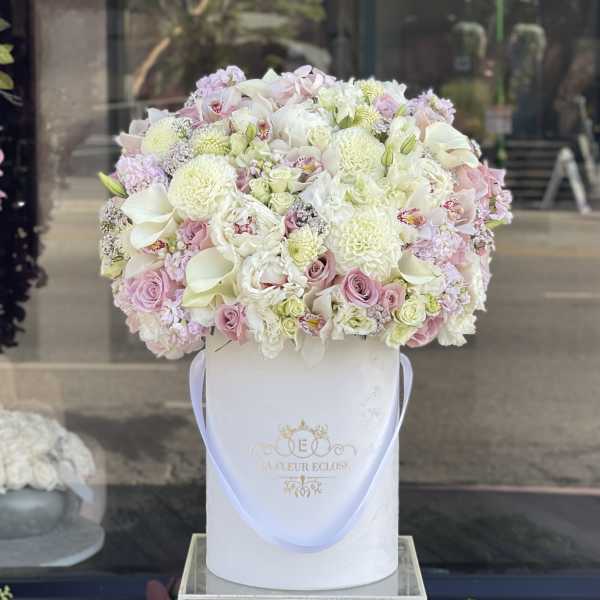Large pastel bouquet in a white hatbox with a ribbon handle