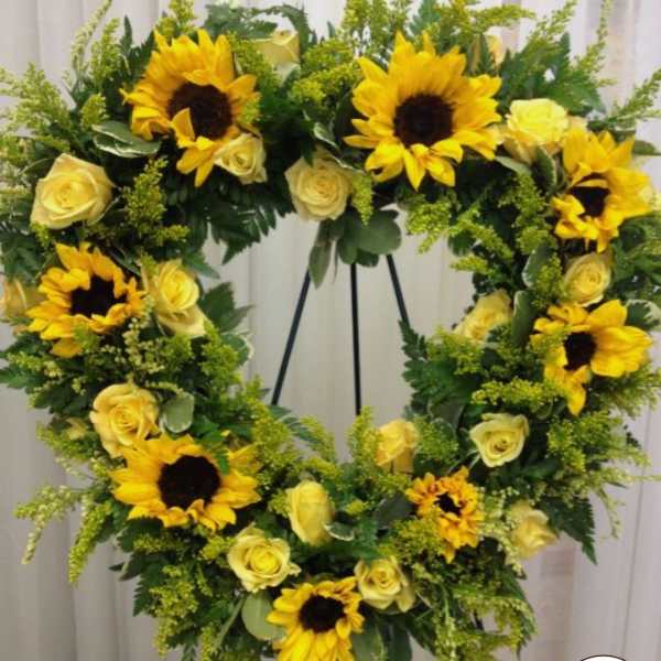 Standing wreath of yellow sunflowers and pale yellow roses on a metal easel