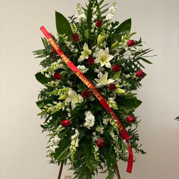 Standing floral spray with red roses, white lilies, and a red ribbon