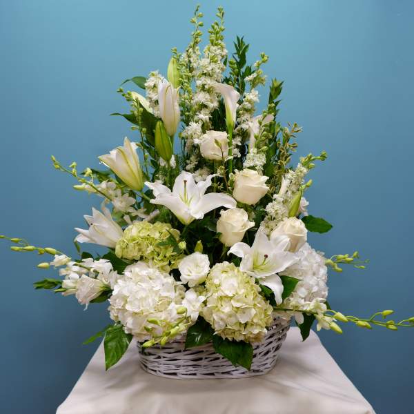 White lilies and roses arranged in a white basket
