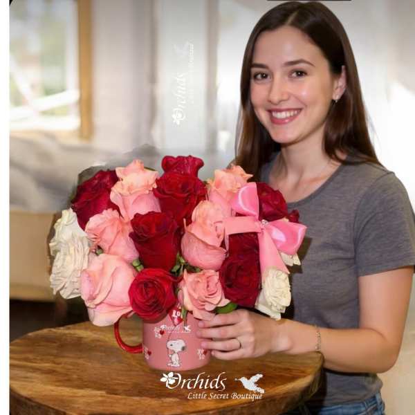 Woman holding a pink mug filled with red and pink roses