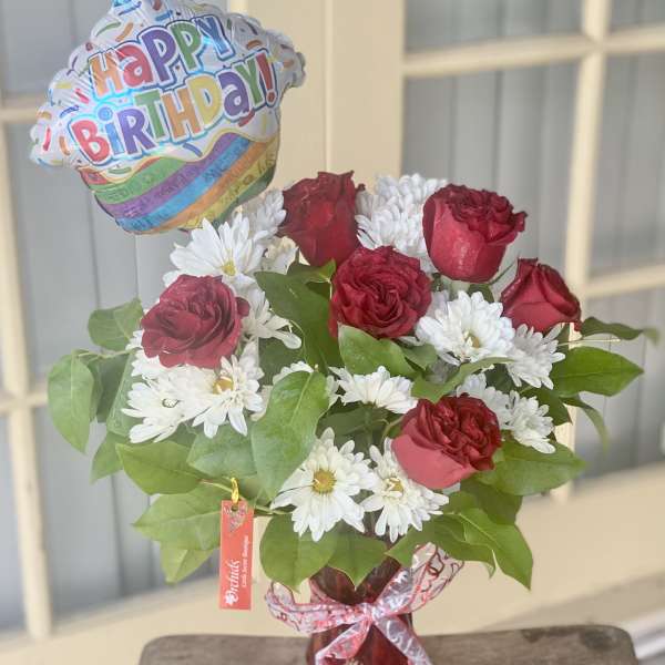 Red roses and white daisies in a vase with a birthday balloon
