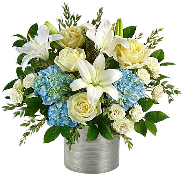 White lilies and cream roses with blue hydrangeas in a silver vase