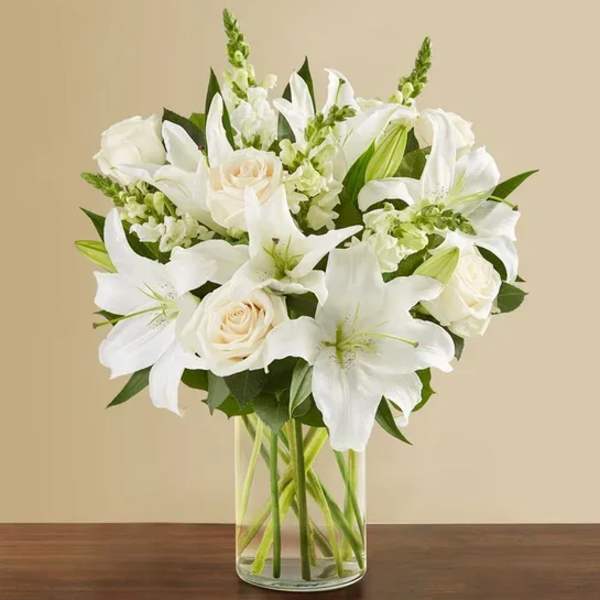 White lilies and roses arranged in a clear glass vase