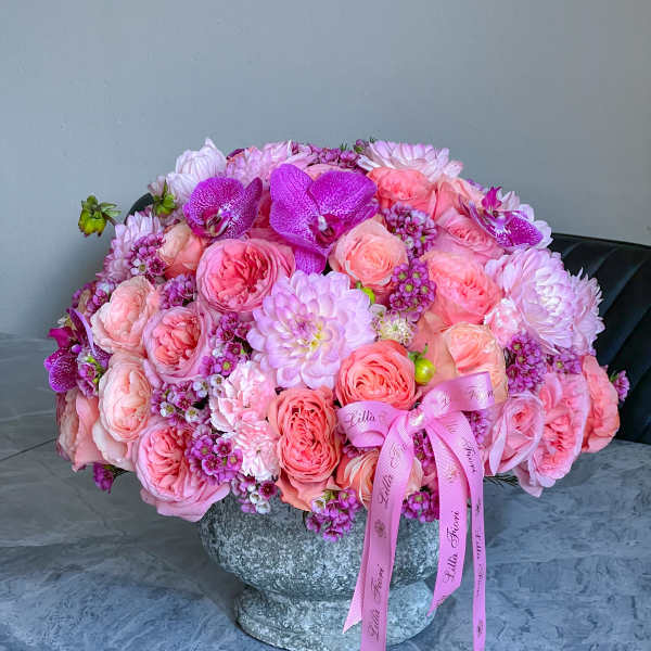 Large pink bouquet in a stone vase with ribbon tails