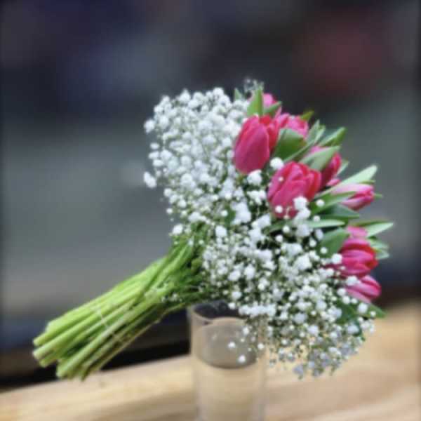 Pink tulip bouquet with baby's breath in a clear glass vase