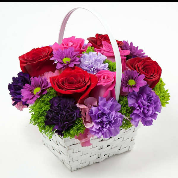 Basket of red, pink, and purple flowers with a white handle