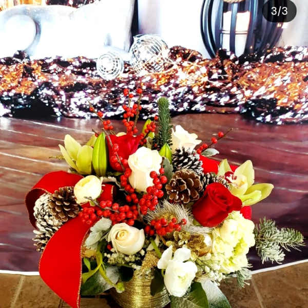 Holiday floral arrangement with red and white roses, lilies, pinecones, and berries