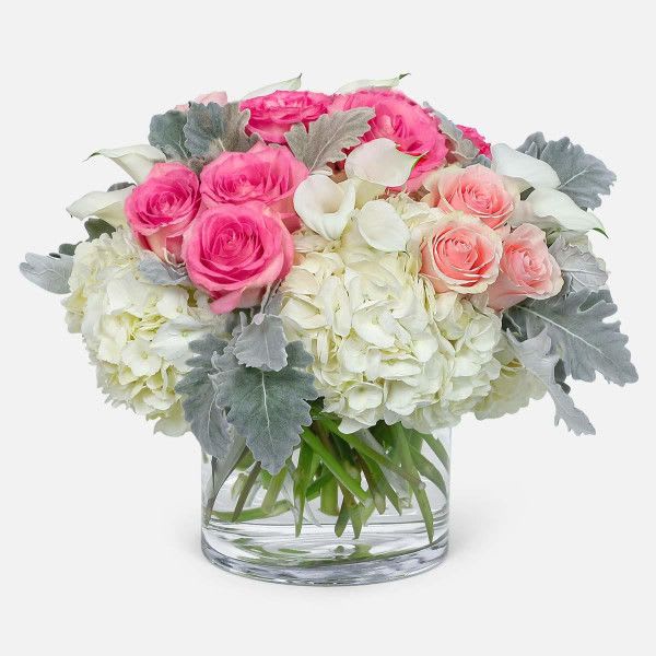 Pink and white roses with hydrangeas in a clear glass vase