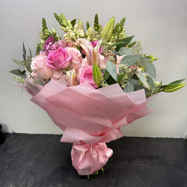 Pink bouquet with roses and lilies wrapped in pink paper