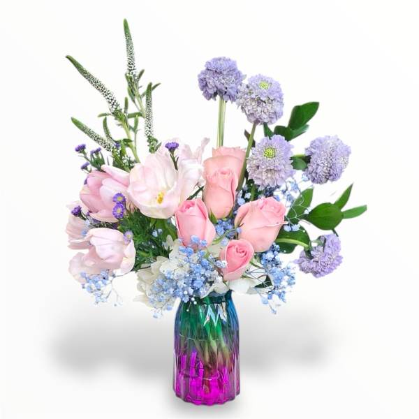 Pink tulips and roses in a colorful glass vase with lavender blooms