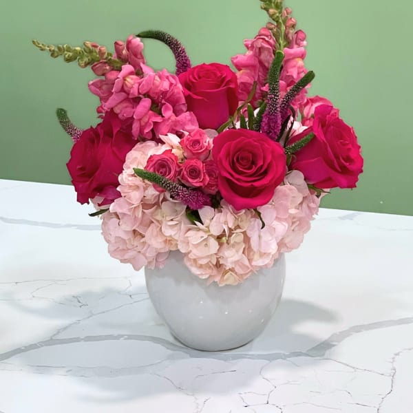 Pink roses and hydrangeas arranged in a white vase