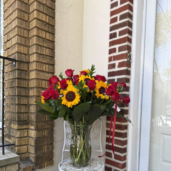Bouquet of red roses and sunflowers in a clear glass vase