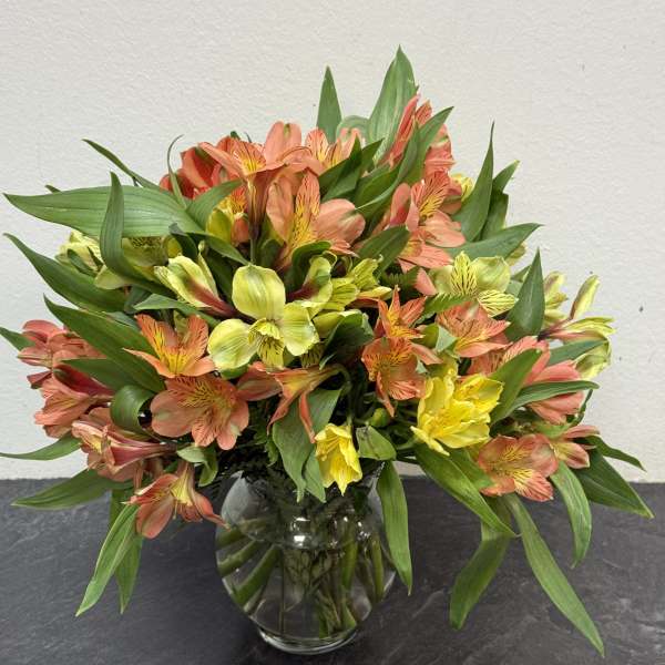 Bouquet of orange, yellow, and pink flowers in a glass vase