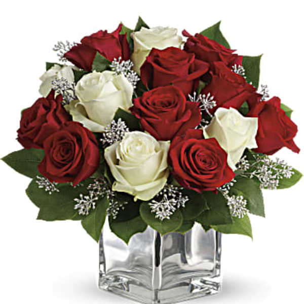 Red and white roses arranged in a clear square vase