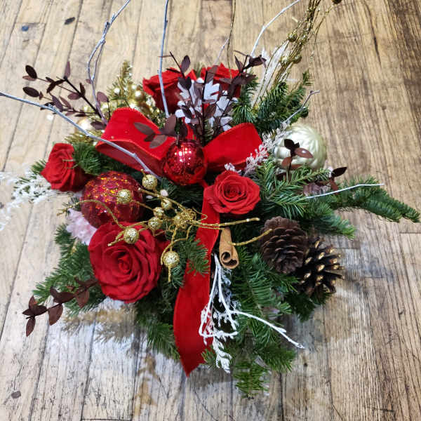 Christmas floral arrangement with red roses, pinecones, and ornaments