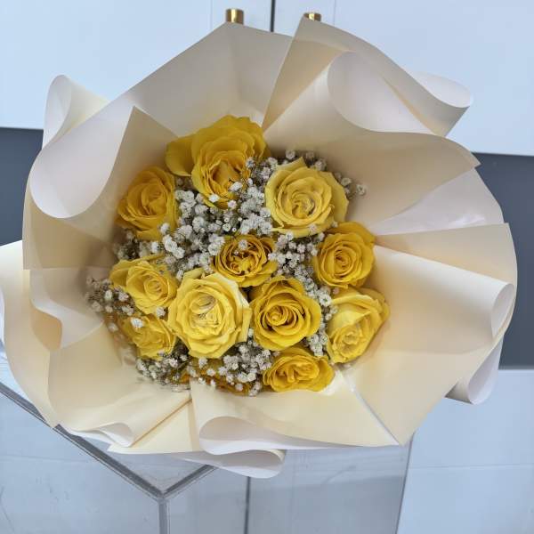 Bouquet of yellow roses wrapped in cream paper