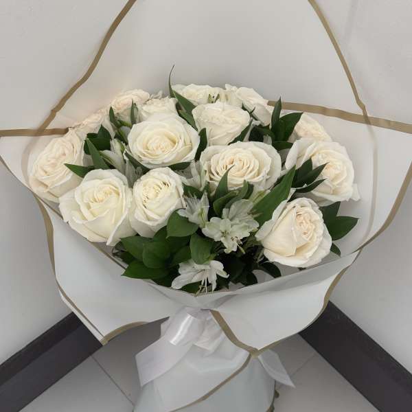 Bouquet of white roses with small white filler flowers wrapped in white paper