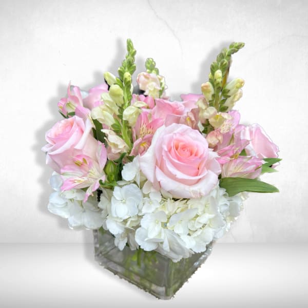 Pink roses and white hydrangeas in a clear square vase