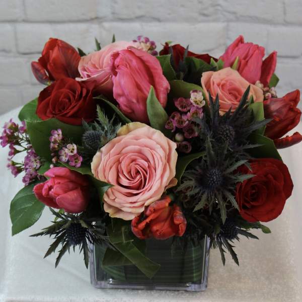 Bouquet of pink and red roses in a square glass vase
