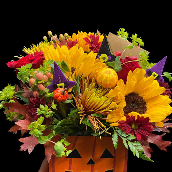 Halloween bouquet in a jack-o'-lantern container with sunflowers and red flowers