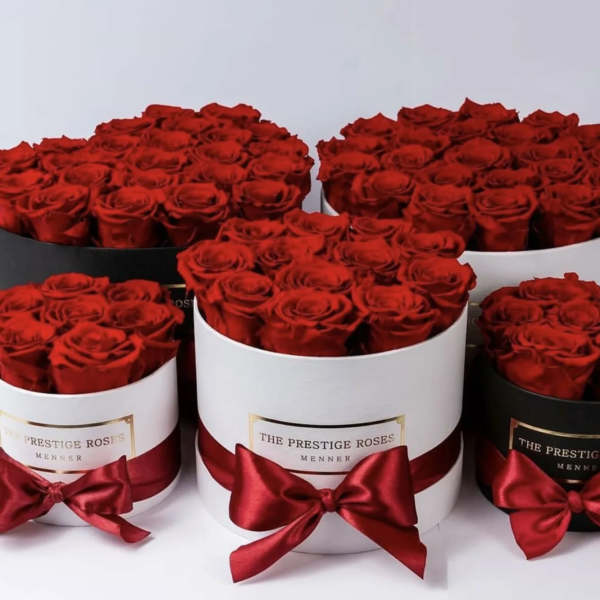 Red roses arranged in round hat boxes with satin bows