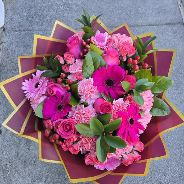 Pink bouquet with roses, gerbera daisies, and carnations in decorative wrap