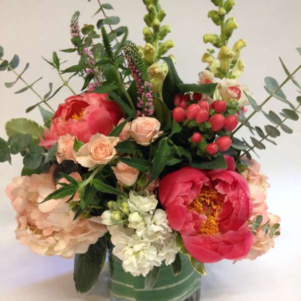 Mixed bouquet in a square glass vase with pink peonies and peach roses