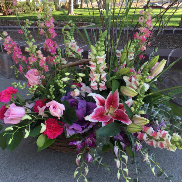 Basket arrangement with pink roses, lilies, and snapdragons