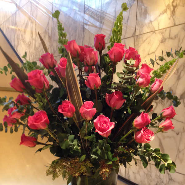 Tall bouquet of pink roses in a clear glass vase