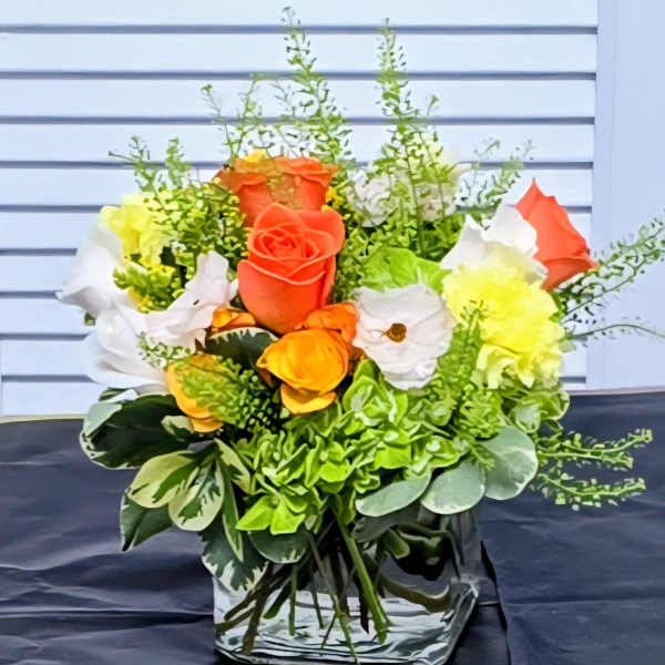 Bouquet of orange, white, and yellow roses in a clear vase