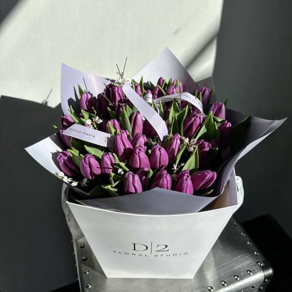 Bouquet of purple tulips wrapped in white and lavender paper