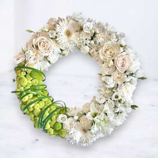 Circular floral wreath with white and cream blooms and a bright green section