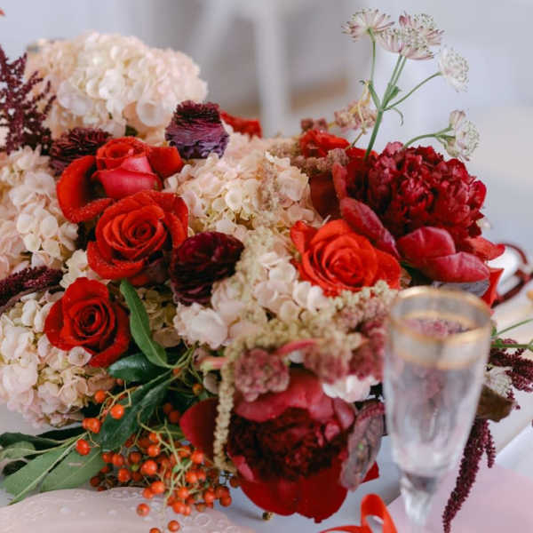 Red roses and pale hydrangeas arranged with anthuriums on a table