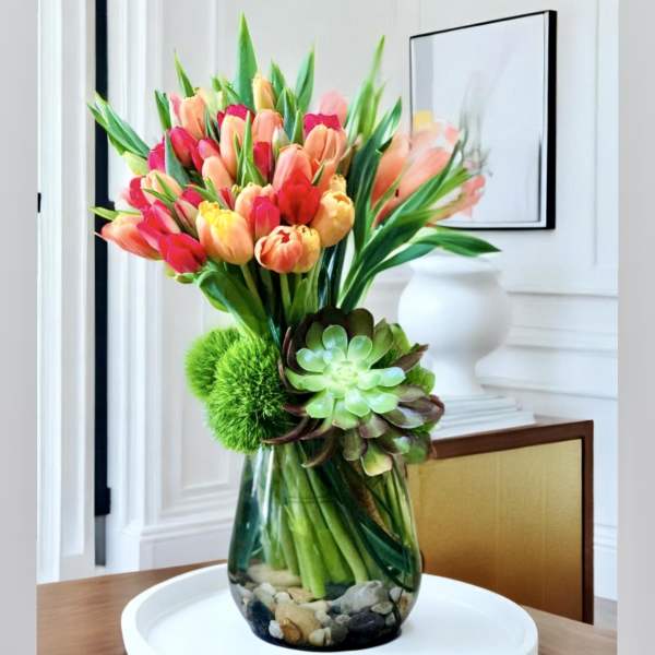 Bouquet of colorful tulips in a glass vase with succulents