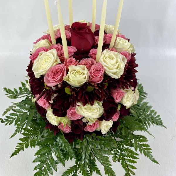 Round rose arrangement with tall taper candles and fern foliage