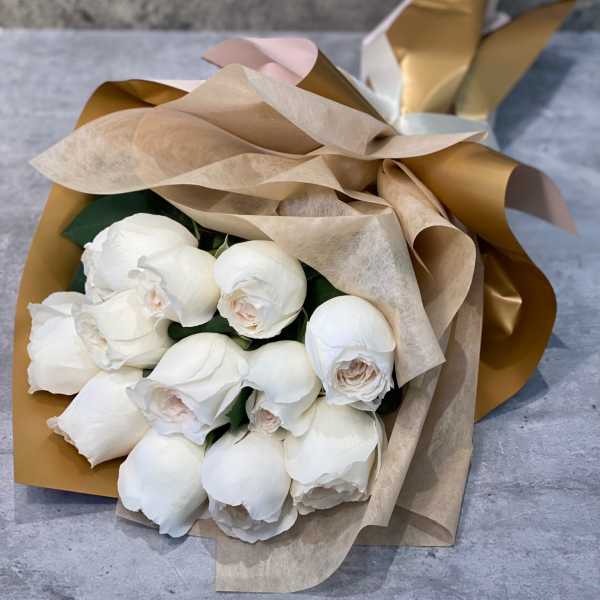 Bouquet of white roses wrapped in tan and gold paper