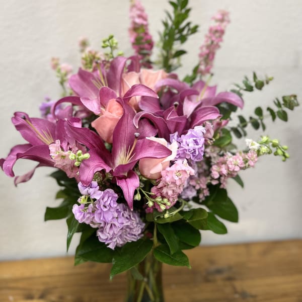 Pink lilies and lavender flowers in a glass vase