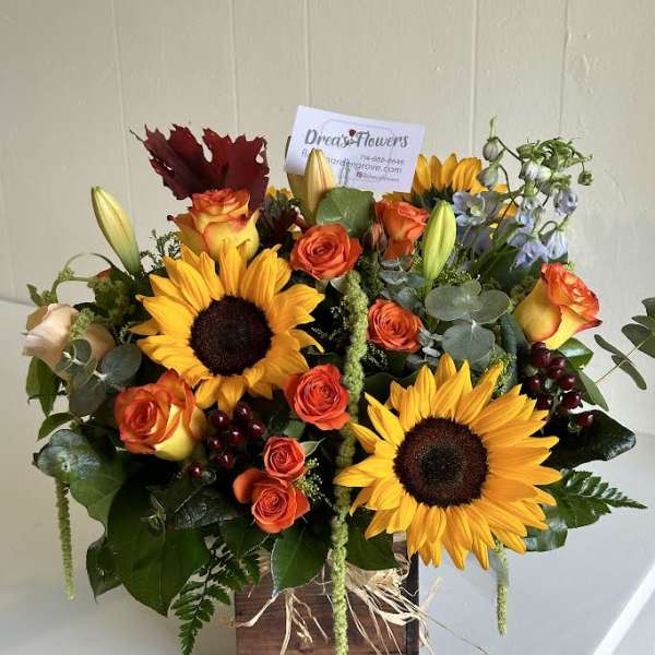 Bouquet of sunflowers and orange roses in a wooden box