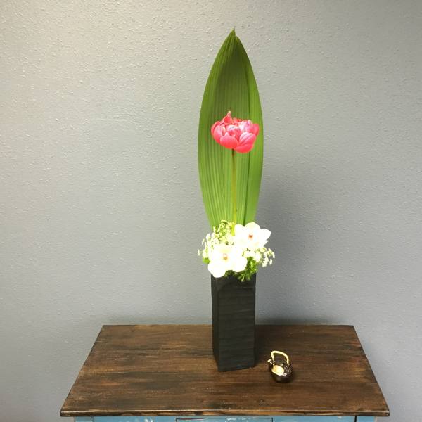 Tall floral arrangement with a pink bloom and white flowers in a black vase