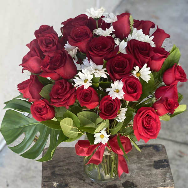 Bouquet of red roses and white daisies in a glass vase