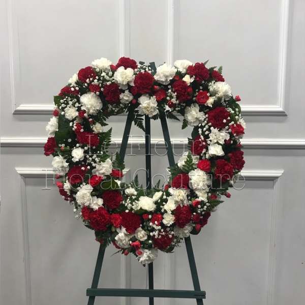 Heart-shaped wreath of red and white carnations on an easel